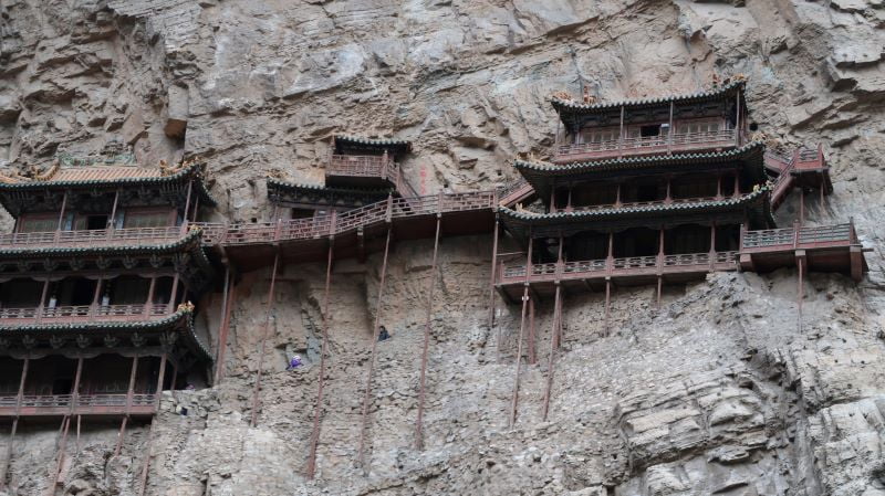 它看似卡在懸崖邊，但實際上是由高蹺支撐的，為佛、道、儒三教合一的寺廟。