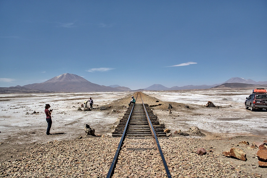 玻利維亞上的白色鹽沼 Uyuni:行走在地球上最大的鏡子 — 烏尤尼完全旅遊攻略 19 途中的鐵路休息站,這條鐵軌好像在通往無止境的地平線。背景有幾座火山包含奧亞圭火山。